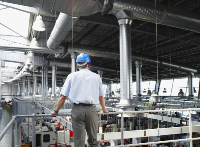 Businessman in hard-hat looking at factory floor