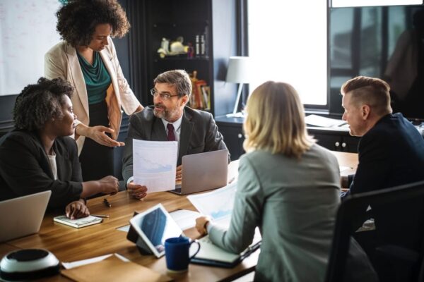 formal business meeting in tight conference room with 5 professionals