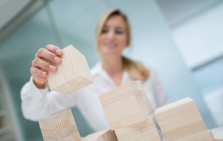 Successful business woman building a project with wooden cubes at the office