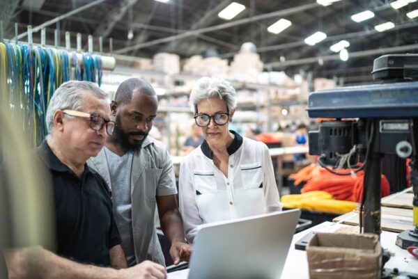 three factory workers gathered in front of laptop