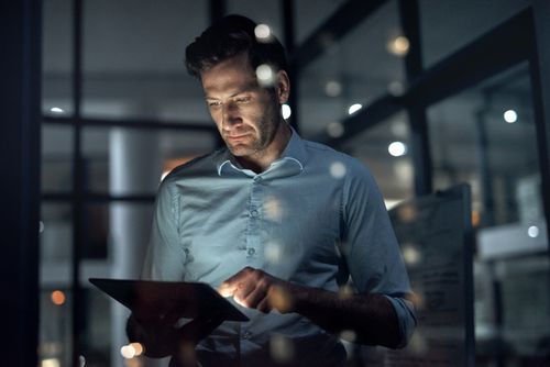 late night worker in office looking at tablet