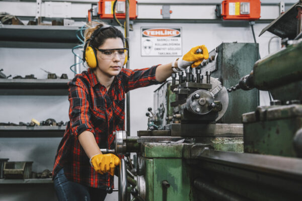 Young lathe worker woman working with milling machine in factory