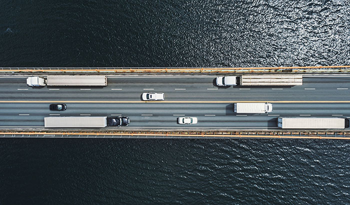 Aerial drone view of semi trucks on suspension bridge. Composite image.