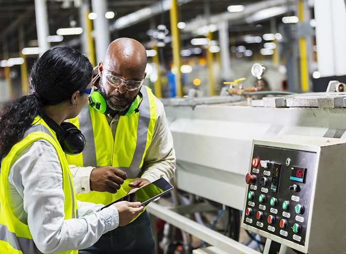 Multiracial workers in factory at machine control panel