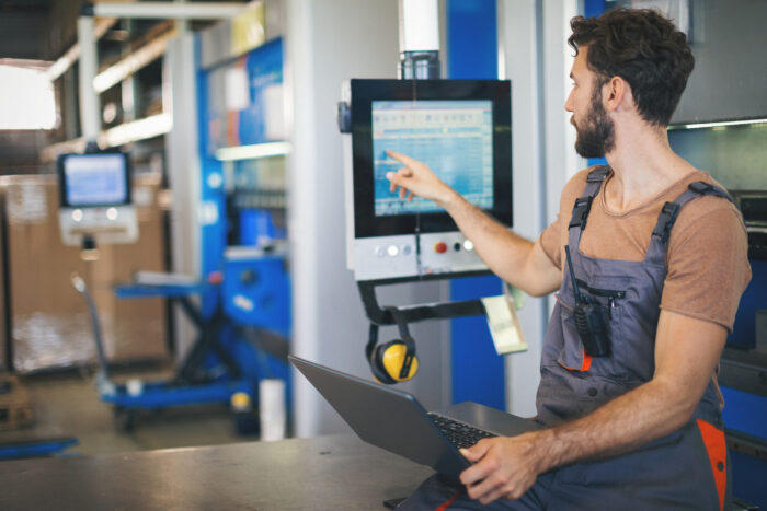 Young man setting the machines in factory