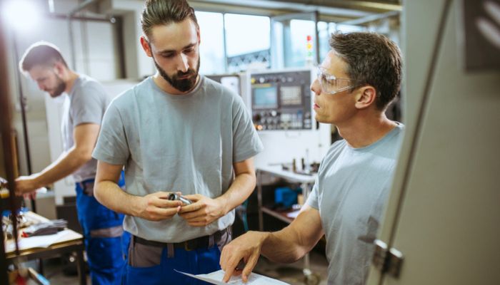 Workers in factory explaining supervisor process and examining quality control