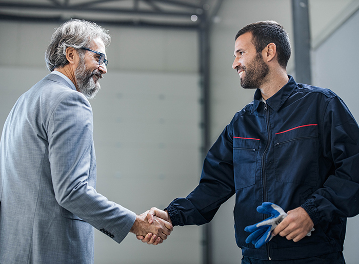 Happy inspector shaking hands with manual worker.