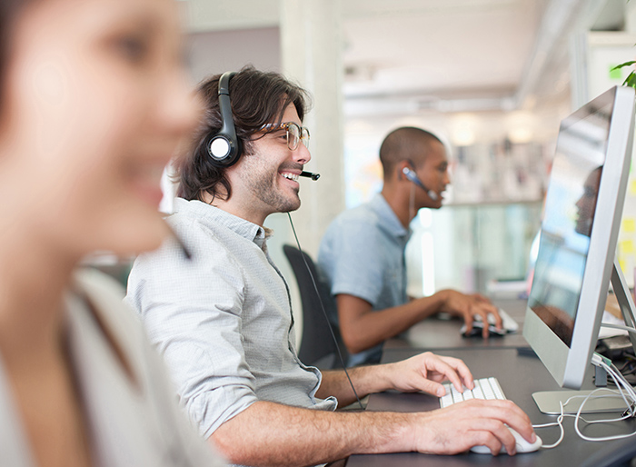 Business people with headsets working at computers in office