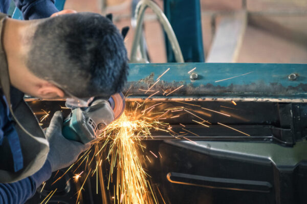 Young man mechanical worker repairing an old vintage car body